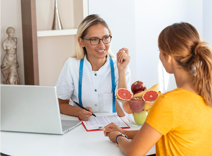Female nutritionist giving consultation to patient making diet plan in weight loss clinic